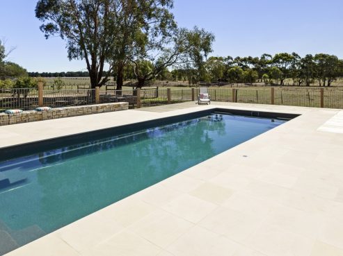 Compass Pools Contemporary swimming pool with tiling around the swimming pool