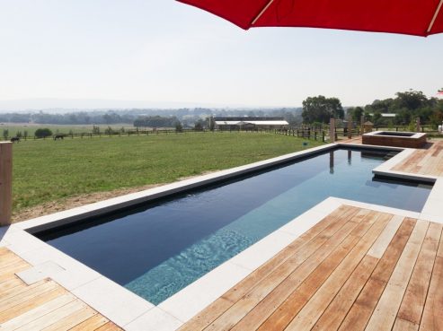 Compass Pools Fastlane fibreglass pool partially above the ground with external steps