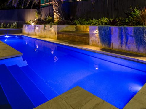 Compass Pools Fastlane lap pools and spa combo with pool lights on