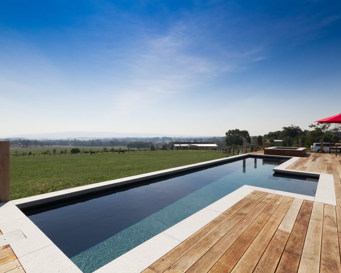 Partially above ground pools Compass Pools Australia Fastlane lap pool installation 12.3m in Slate colour with an X Trainer spa